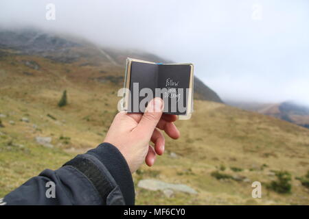 Reise - Travel Concept, Reisender hält ein Buch mit einer Inschrift - Ihre Träume folgen Stockfoto