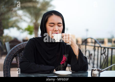 Muslimische Frau mit einer Tasse Kaffee in einer Bar im Freien Stockfoto