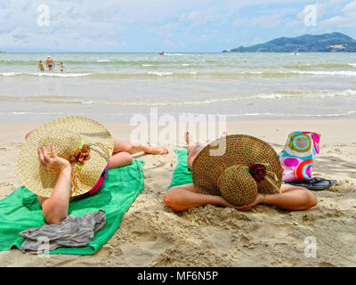 Frauen mit großen Sun hats beim Sonnenbaden am Strand, Patong Beach, Phuket, Thailand, Thailand Stockfoto