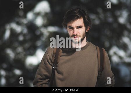 Jungen gutaussehenden Mann Wandern oder Skifahren in einem verschneiten Wald Stockfoto