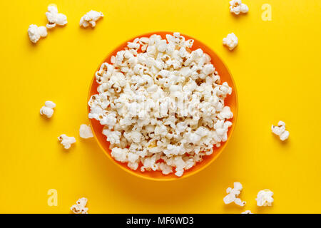 Popcorn in eine orange Schüssel auf gelben Hintergrund. Bild horizontal. Ansicht von oben. Stockfoto