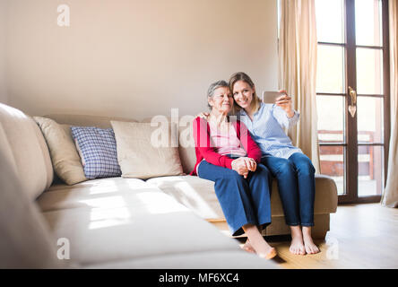 Ältere Großmutter und Enkelin mit Smartphone zu Hause. Stockfoto