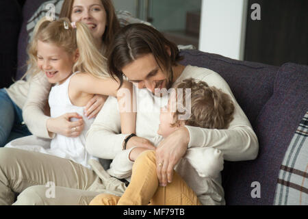 Glückliche Eltern und Kinder lachen Spaß kitzeln auf dem Sofa Stockfoto