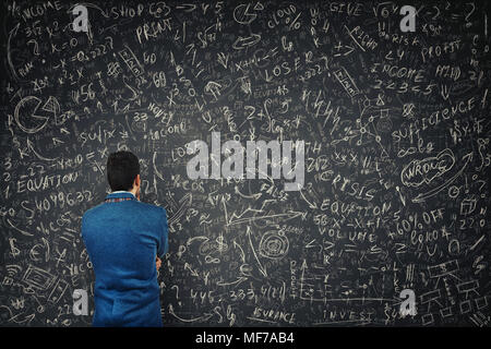 Rückansicht eines verwirrten Geschäftsmann vor einem riesigen Tafel versuchen Mathematik Berechnung, Formeln und Gleichungen zu lösen. Das Denken des Projekts Stockfoto
