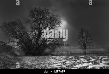 Sonne scheint durch Regenwolken, Monochrom Stockfoto