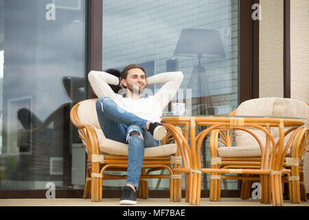 Lächelnd Mann entspannt genießen angenehmen Morgen sitzen auf der Terrasse Stockfoto
