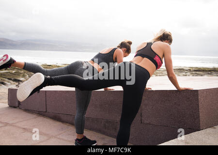 Zwei junge Frauen erhalten zusammen passen, während sie Bein erstreckt sich in sportliche Kleidung Stockfoto