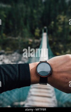 Des Menschen Hand mit Uhr vor Swinging Bridge Stockfoto