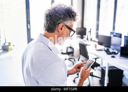 Reife Geschäftsmann im Büro mit smartphone Stockfoto