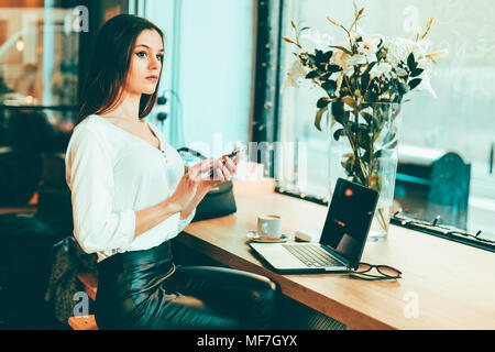 Nachdenkliche junge geschäftsfrau mit Smartphone in einem Coffee Shop Stockfoto