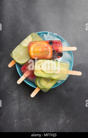 Verschiedene Früchte Eis am Stiel an der Schale mit Eiswürfeln Stockfoto