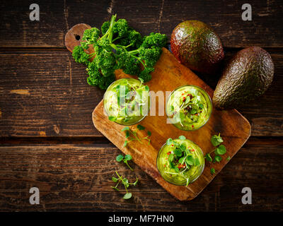 Gläser Avocadocreme mit Chili Flocken, Kresse und Petersilie Stockfoto