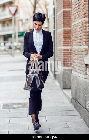 Porträt der jungen Geschäftsfrau mit Tasche wandern auf Pflaster Stockfoto