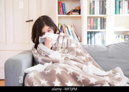 Krankes Mädchen sitzen auf der Couch zu Hause blasen Nase Stockfoto