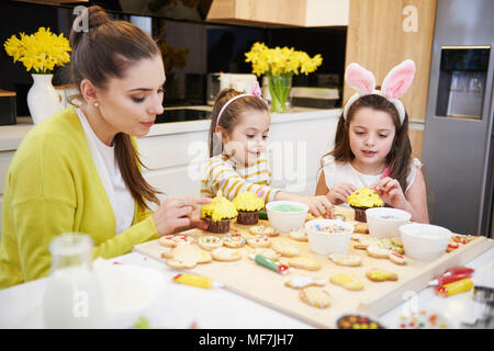 Mutter mit Töchtern Dekoration Ostern Kekse und Muffins in der Küche Stockfoto