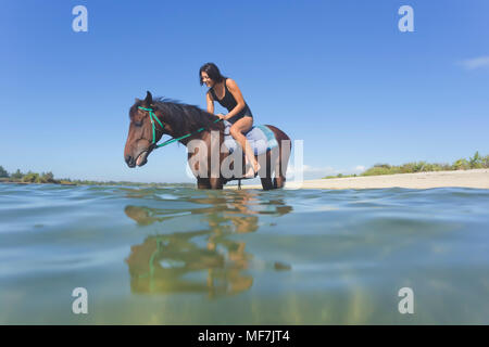 Indonesien, Bali, Frau sitzt auf Pferd, in Wasser Stockfoto
