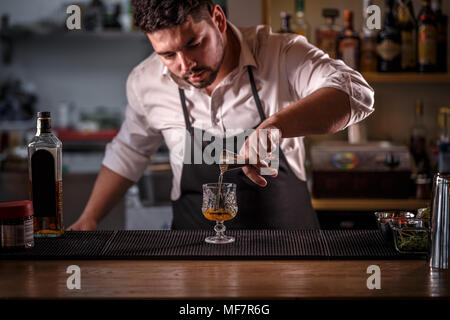 Barkeeper gießt Alkohol aus einer Messung von Glas in ein Glas Stockfoto