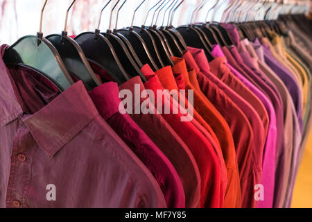 Männliche mens Shirts in der Farbe bestellen auf Kleiderbügeln auf einem Shop Kleiderschrank rail sortiert Stockfoto