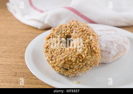 Lebensmittel und Bäckerei, Teller mit leckeren süßen Donuts mit Erdbeer-Marmelade, Schokolade und Erdnüssen Toppings Stockfoto