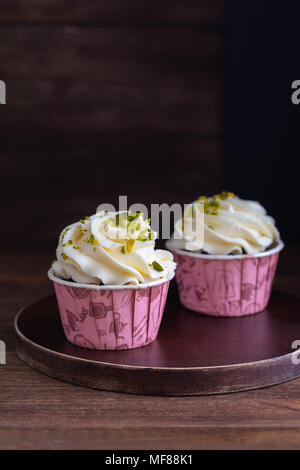 Hausgemachte Schokolade Muffins oder Cupcakes mit Vanillecreme und Pistazien auf dem hölzernen Hintergrund, getönt Stockfoto