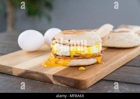 Canadian Bacon, Ei und Käse Breakfast Sandwich mit Englisch muffin auf Schneidebrett mit Gabel Stockfoto