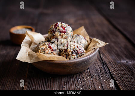 Gesunde Rohstoffe Haferflocken Kugeln mit Chia Samen, getrocknete Cranberries, Kokosraspeln, Leinsamen und Honig Stockfoto