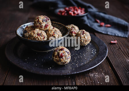 Gesunde Rohstoffe Haferflocken Kugeln mit Chia Samen, getrocknete Cranberries, Kokosraspeln, Leinsamen und Honig Stockfoto