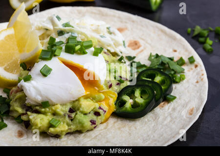 Pochierte Eier und guacamole Sauce auf Mehl Tortilla, mexikanischen Stil Frühstück Stockfoto