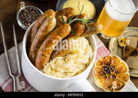 Traditionelle deutsche Würstchen mit Krautsalat, Senf und Bier. Bratwurst und Sauerkraut. Stockfoto