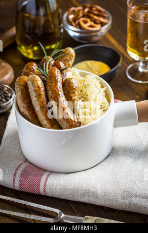 Traditionelle deutsche Würstchen mit Krautsalat, Senf und Bier. Bratwurst und Sauerkraut. Stockfoto