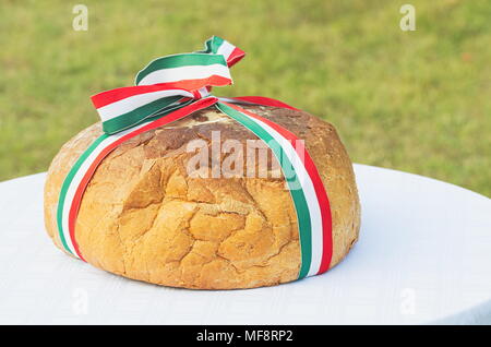 Ganze Brot mit ungarische Trikolore Band auf einem weißen Tuch im Freien Stockfoto