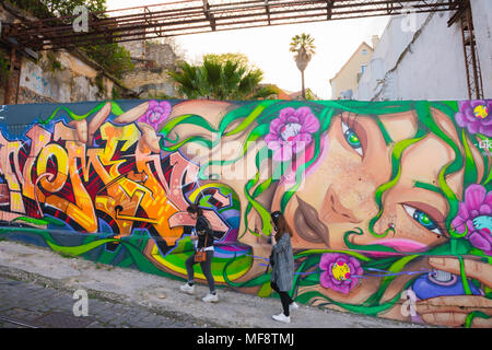 Lissabon Portugal Straße, Blick auf zwei junge Frauen, die an einem bunten Kunstwerk an einer Wand im Baixa-Viertel von Lissabon, Portugal, vorbeigehen. Stockfoto