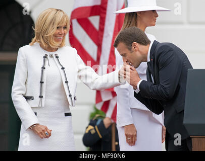 Präsident Emmanuel längestrich von Frankreich küsse die Hand seiner Frau, Brigitte Längestrich, nach Abschluss der Begrüßungszeremonie auf dem Rasen des Weißen Hauses in Washington, DC am Dienstag, 24. April 2018. First Lady Melania Trump ist dargestellt hinter ihnen. Credit: Ron Sachs/CNP/MediaPunch Stockfoto