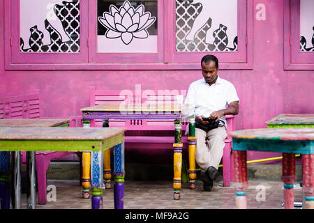 Ein Mann auf seinem Mobiltelefon an ein geschlossenes Restaurant in Souq Mubarakiya, Kuwait Stockfoto