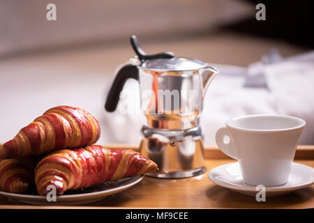 Frühstück im Bett. Tablett mit Kaffee und Croissants. Stockfoto