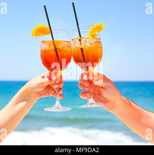 Zwei cocktail Gläser in der Hand auf das Meer im Hintergrund. Sommer Urlaub Konzept Stockfoto