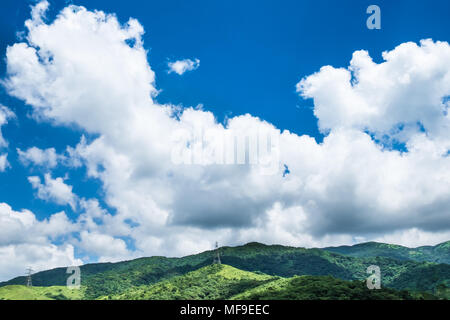 Cumulus Wolken über dem Berg. Hing Spannung power line mit Strommasten vorbei durch die Berge. Stockfoto