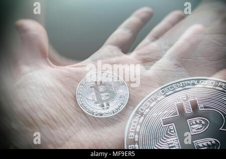 Hand, die eine transparente Bitcoin. Tonned Double Exposure. Stockfoto