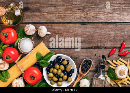 Zutaten für die Zubereitung von Pasta, Spaghetti, Basilikum, Tomaten, Oliven und Olivenöl auf Holz- Hintergrund. Ansicht von oben. Kopieren Sie Platz. Stockfoto