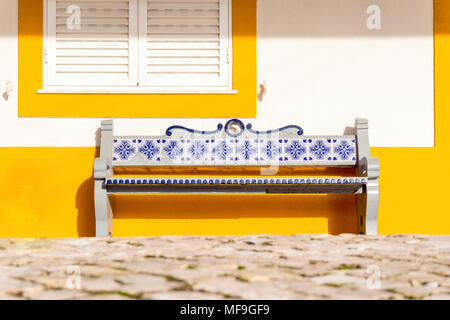 Sitzbank mit traditionellen Fliesen genannt Azulejos vor gelben Haus dekoriert, Portugal Stockfoto