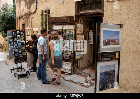 Touristen, die auf der Suche an einem Baugruppenträger oat ein Souvenirgeschäft in einer engen Straße Zitadelle von Calvi auf Korsika, einer französischen Insel vor der Südküste Frankreichs in der M Stockfoto