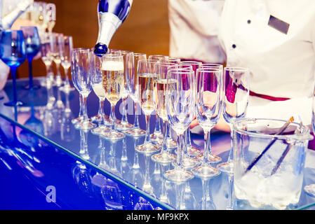 Kellner gießen Persönliche serviert Champagner Gläser auf hellen blauen stehen. Catering bei Veranstaltungen, Treffen, Party, Hochzeiten. Selektive f Stockfoto
