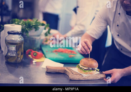 Meisterkoch, Zahnstocher auf einen Burger im Restaurant Küche Stockfoto