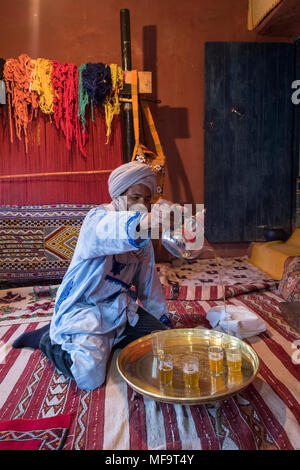 Ein Berber Mann in traditioneller Kleidung gießt Pfefferminztee in seinem Haus, Tinghir, Hoher Atlas, Marokko Stockfoto