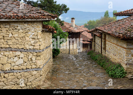 Knysna, Bulgarien - engen, gepflasterten Straßen und rustikalen traditionelle Häuser aus Stein und Holz mit bigroot cranesbill (Geranium macrorrhizum) zusammen. Stockfoto