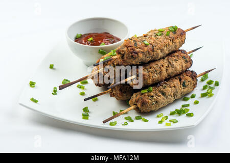 Kebab mit Kräutern auf einem weißen Teller auf weißem Hintergrund Stockfoto