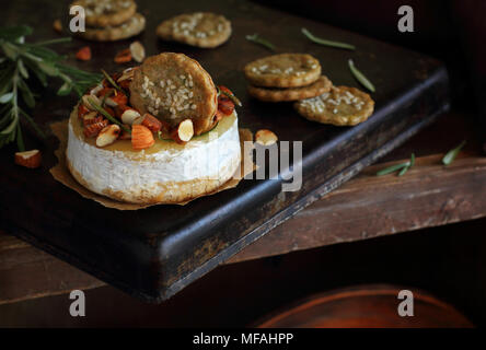 Gebackener Käse mit Mandeln, Rosmarin, Honig und Cracker auf einem Metallauflagefach Stockfoto