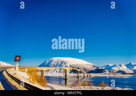 Im Freien von gefrorenen Straßen und informative Zeichen auf einer Seite der Straße, in der Nähe der steinigen Brücke in Lofoten Stockfoto