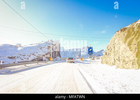 LOFOTEN, NORWEGEN, April, 10, 2018: Im freien Blick auf die gefrorene Straße mit einer informativen Zeichen der Kamera Aufzeichnung der Geschwindigkeit und dem Auto in der Straße mit Schnee im Skjelfjord auf den Lofoten Inseln Stockfoto