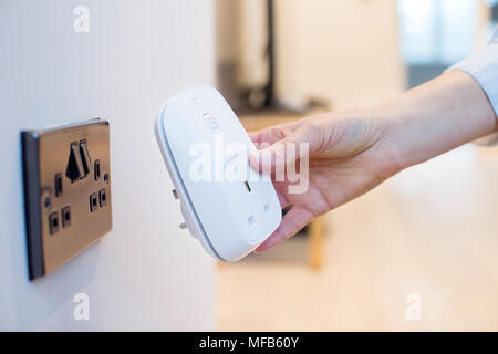 Frau stecken Smart Stecker in die Steckdose zu Hause. Stockfoto
